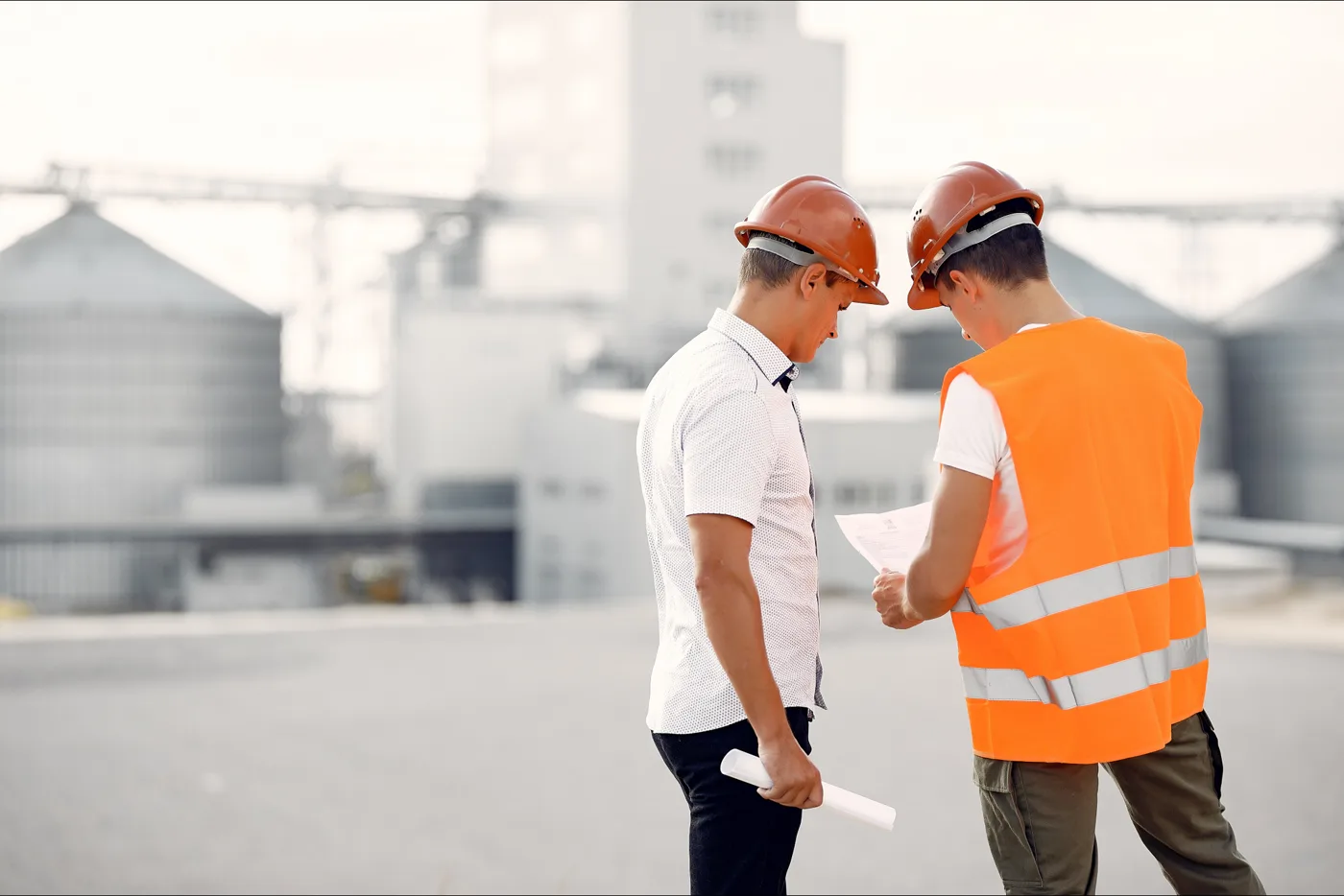 Twee bouwprofessionals bespreken tekeningen op een bouwlocatie